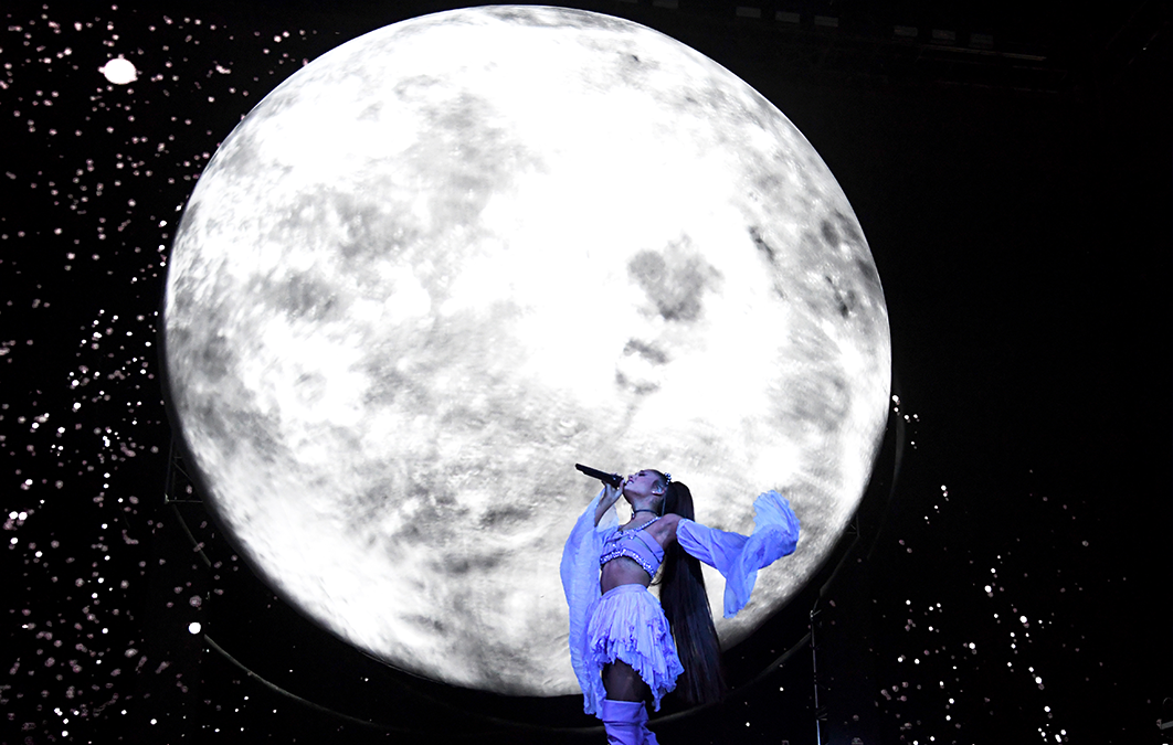 Ariana Grande singing in front on large moon video design